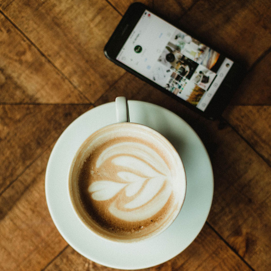 Coffee cup and phone on wood table